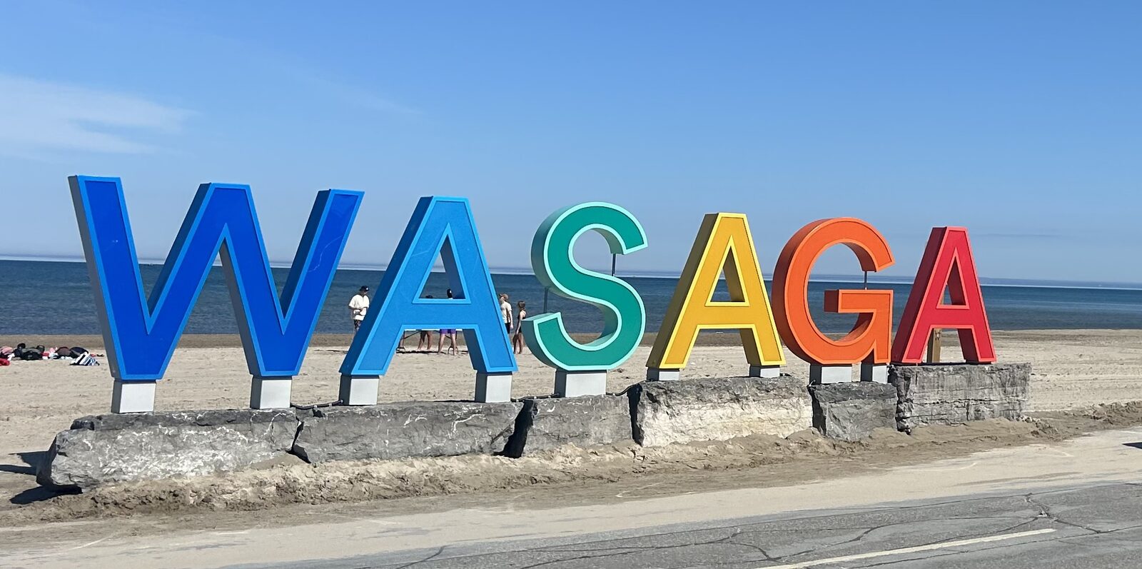 The colourful WASAGA letter installation on the beach in front of Wasaga Beach Provincial Park, with Georgian Bay in the background.